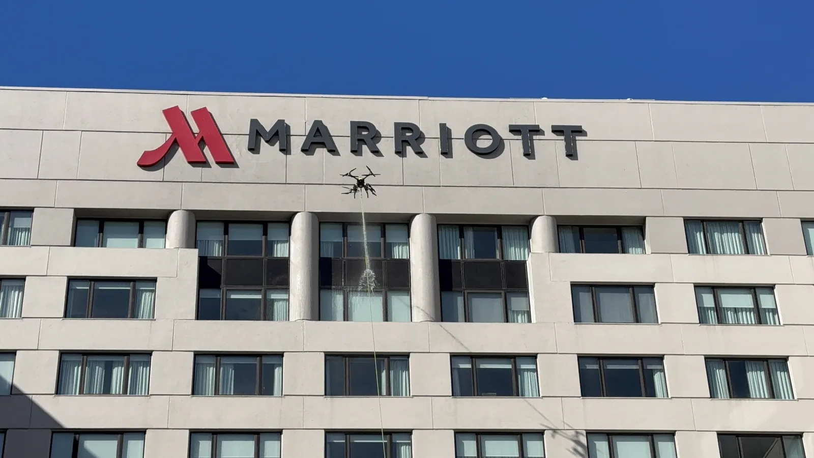 Dron przemysłowy myje ciśnieniowo wielokondygnacyjną elewację hotelu w USA