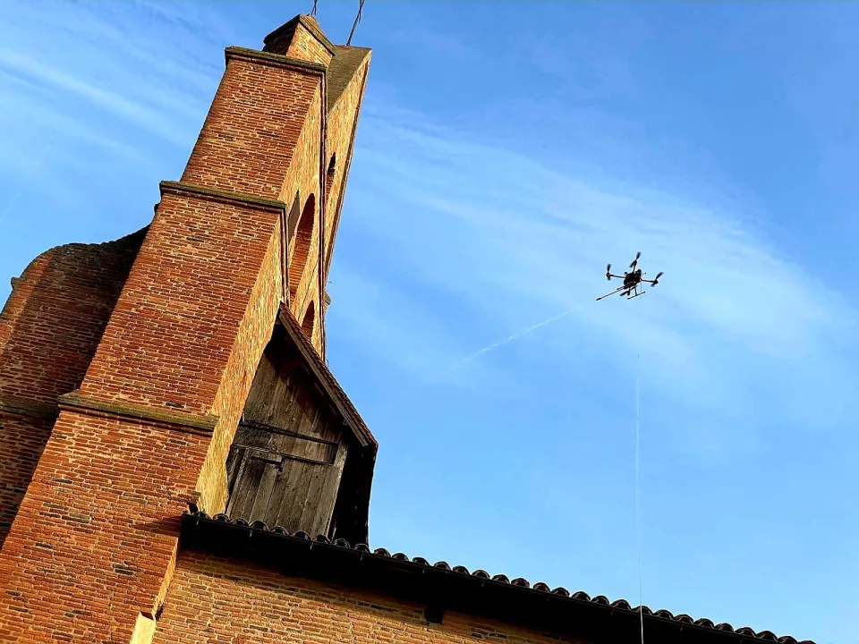 Dron podczas czyszczenia wysokiej ceglanej elewacji kościoła